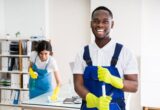 Portrait Of A Happy Male Janitor With Cleaning Equipment In Office