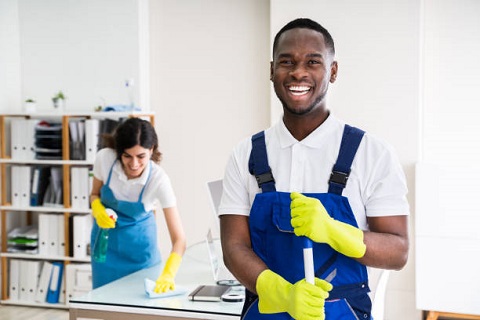 Portrait Of A Happy Male Janitor With Cleaning Equipment In Office